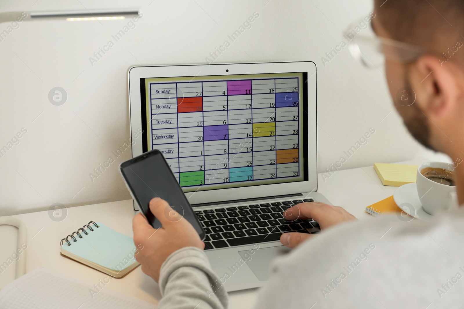 Photo of Young man using calendar app on laptop in office, closeup