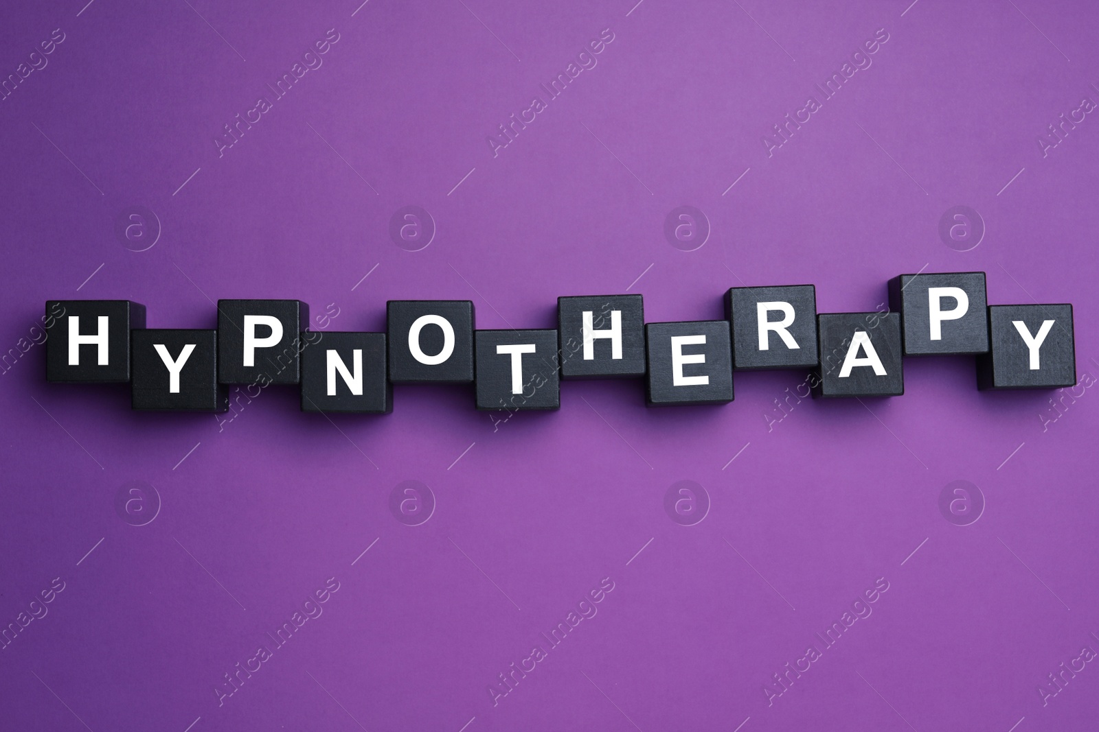 Photo of Black wooden blocks with word HYPNOTHERAPY on purple background, flat lay