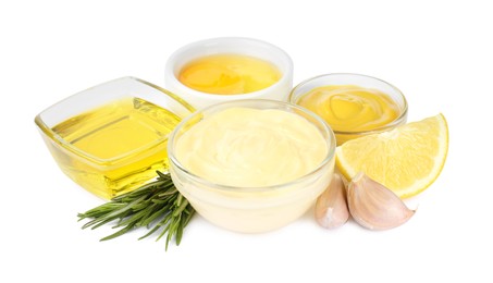 Glass bowl with fresh mayonnaise and ingredients on white background