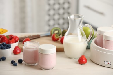 Photo of Portion jars for yogurt maker and different fruits on white wooden table in kitchen