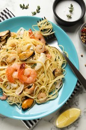 Delicious pasta with sea food served on white marble table, flat lay