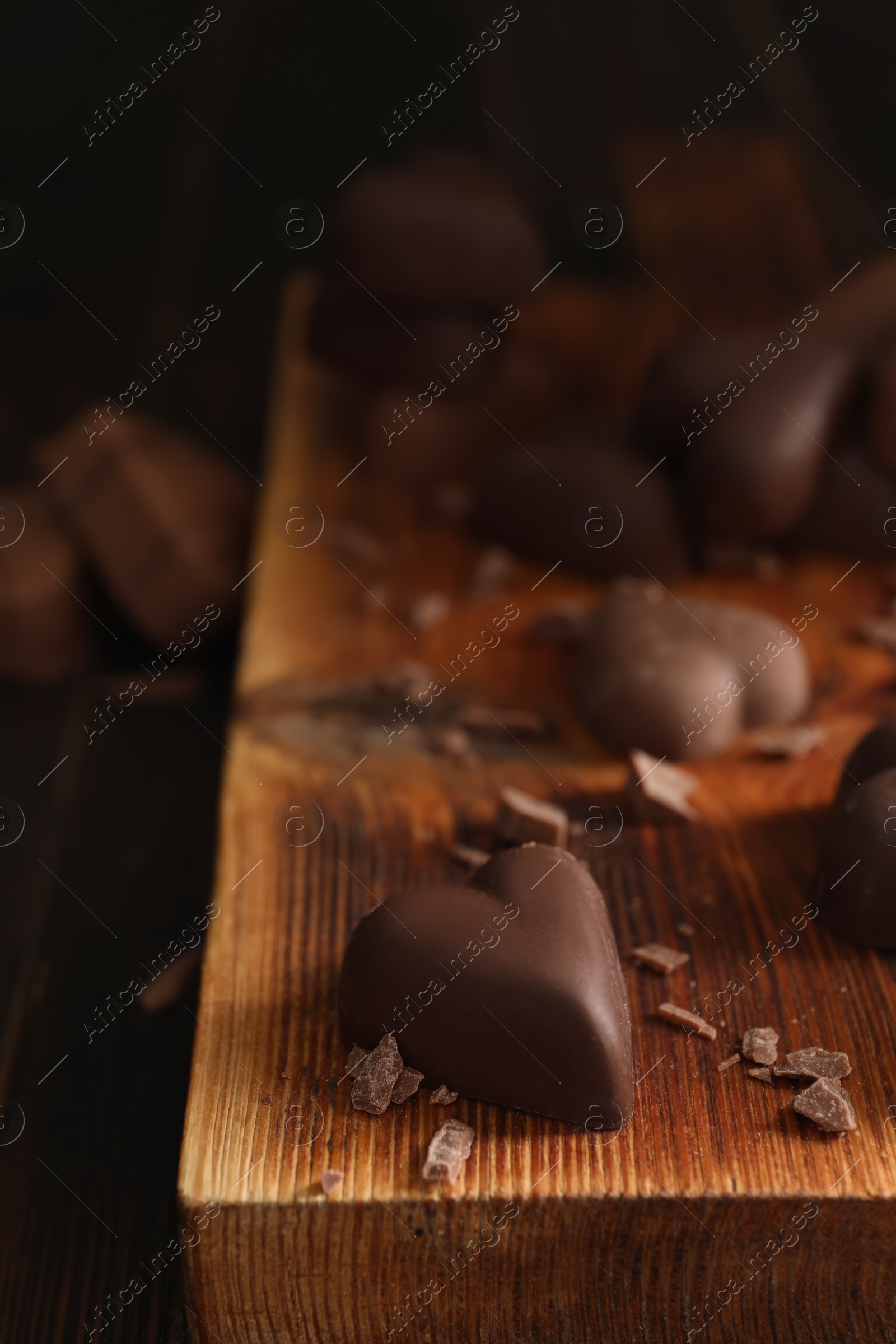 Photo of Beautiful heart shaped chocolate candies on wooden board, closeup with space for text