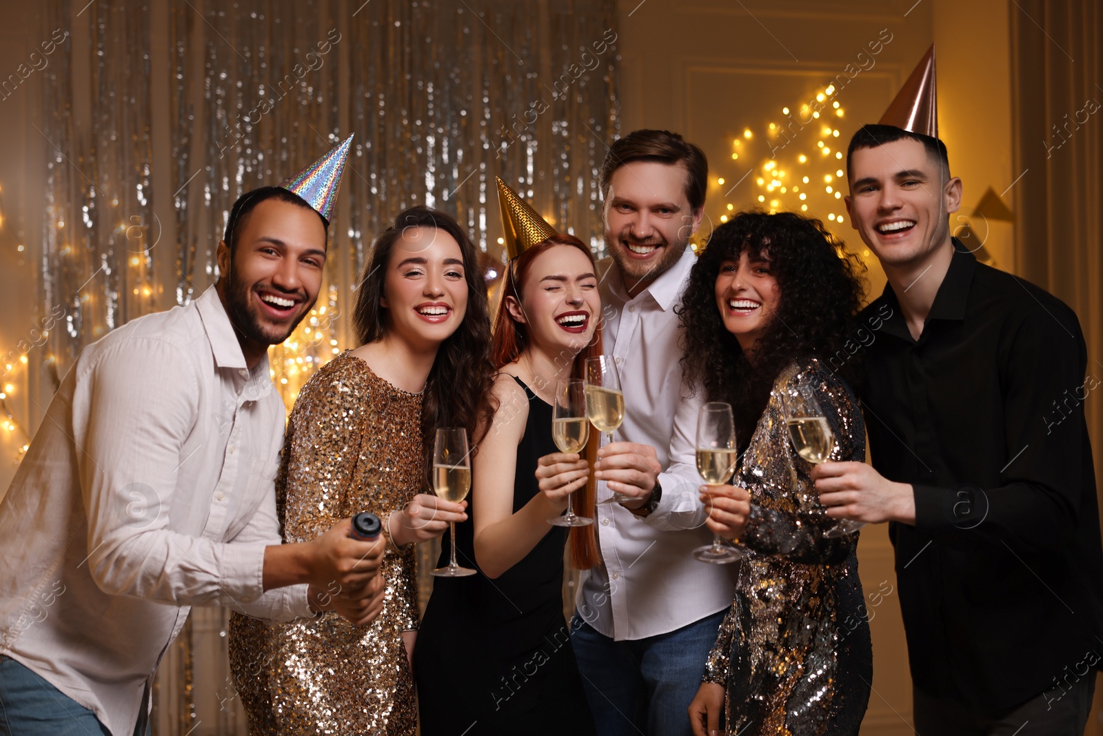 Photo of Happy friends with glasses of sparkling wine celebrating birthday indoors