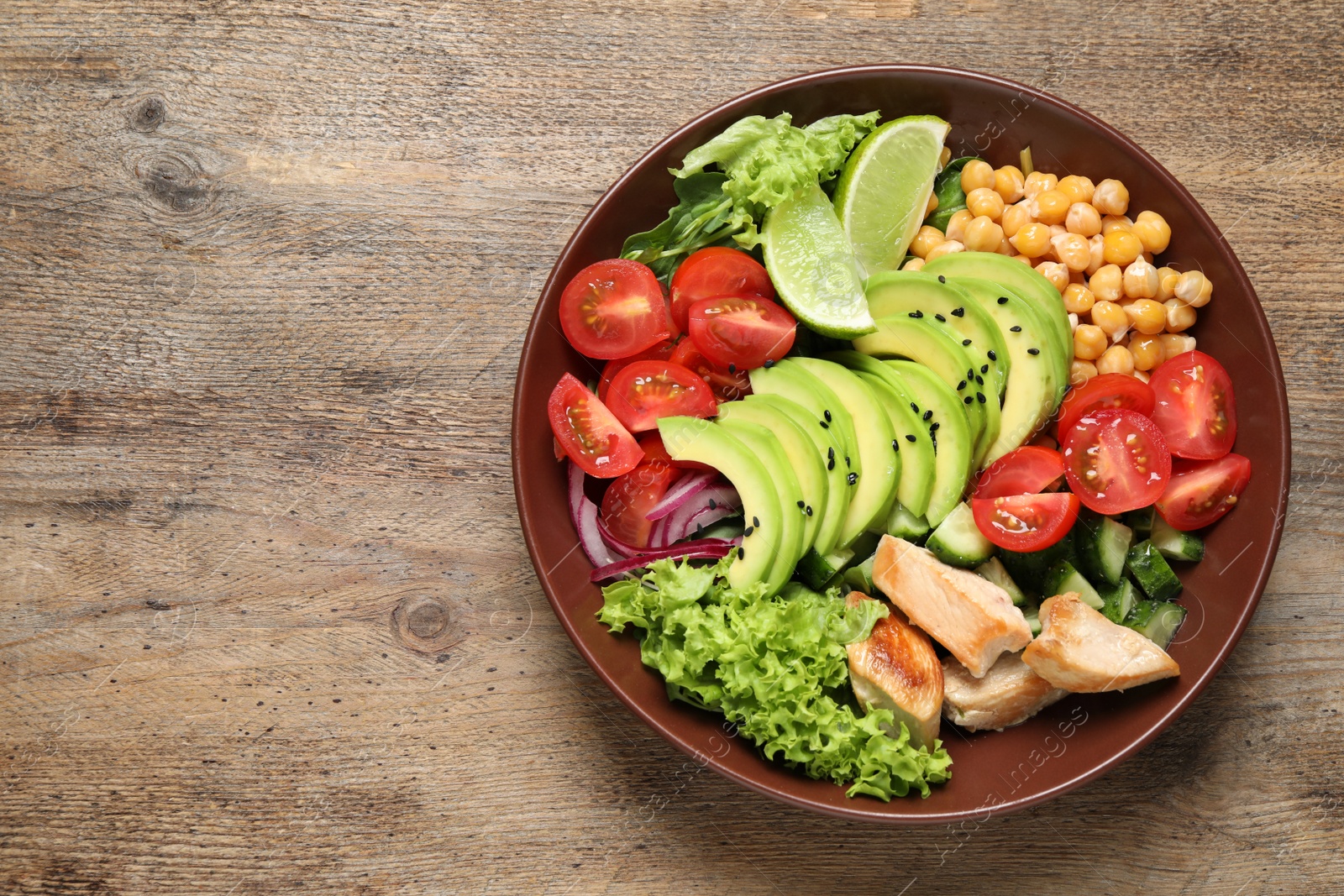 Photo of Delicious avocado salad with chicken on wooden table, top view. Space for text
