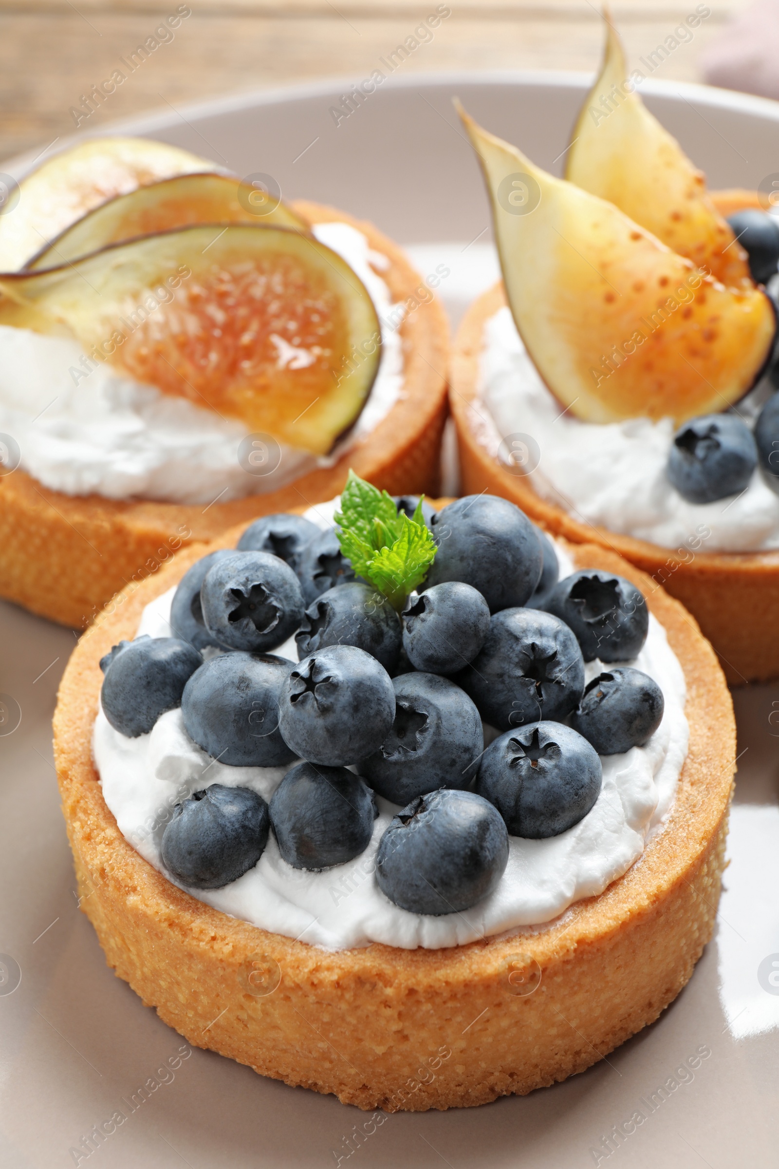 Photo of Tarts with blueberries and figs, closeup. Delicious pastries