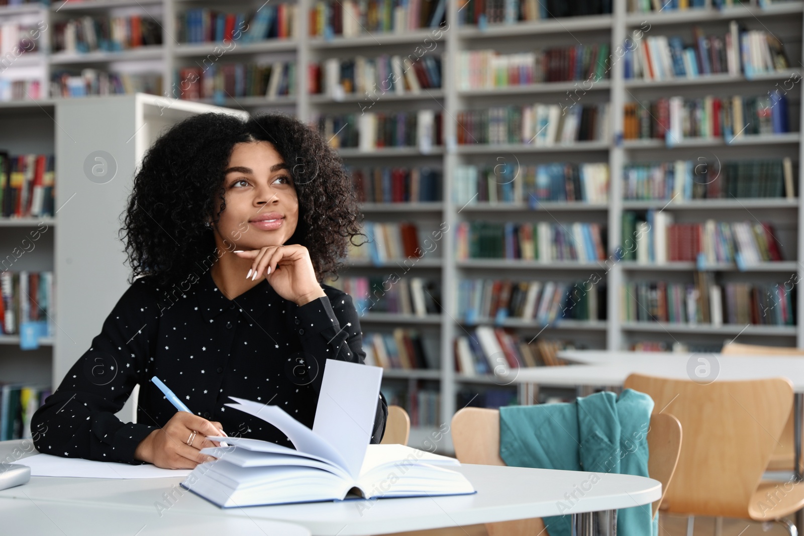 Photo of Young African-American woman studying at table in library