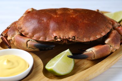 Photo of Delicious boiled crab served with lime and sauce on white table, closeup