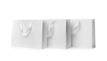 Photo of Paper shopping bags with ribbon handles on white background. Mockup for design