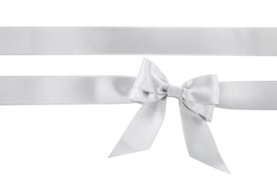 Silver satin ribbons with bow on white background, top view