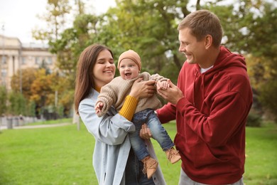 Photo of Happy parents with their adorable baby walking in park