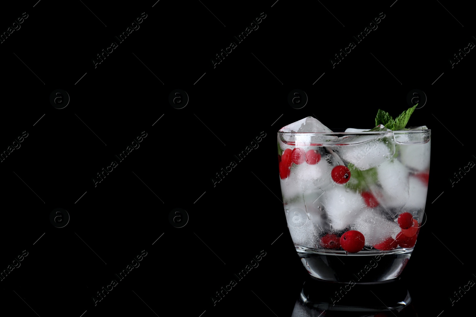 Photo of Glass of cocktail with vodka, ice and cranberry on black background. Space for text