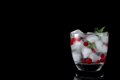 Glass of cocktail with vodka, ice and cranberry on black background. Space for text