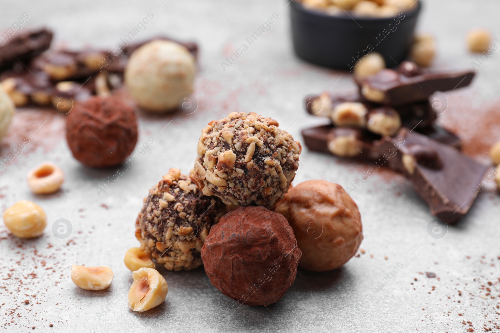 Photo of Tasty chocolate candies and nuts on light grey table