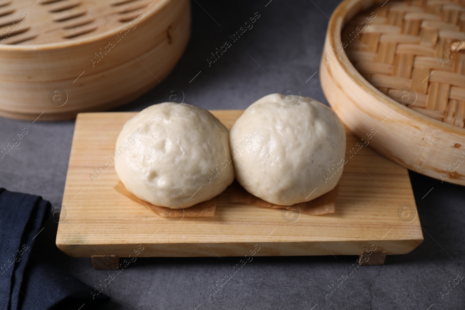 Photo of Delicious Chinese steamed buns on grey textured table, closeup