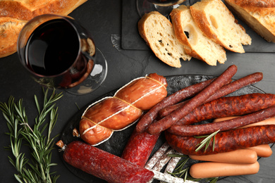 Photo of Different tasty sausages on black table, flat lay