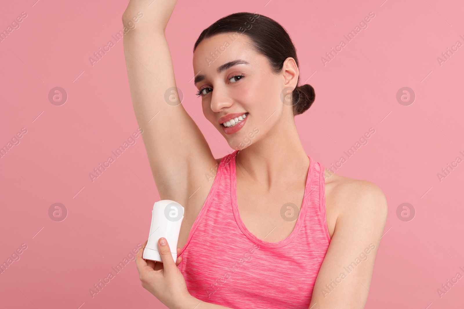 Photo of Beautiful woman applying deodorant on pink background