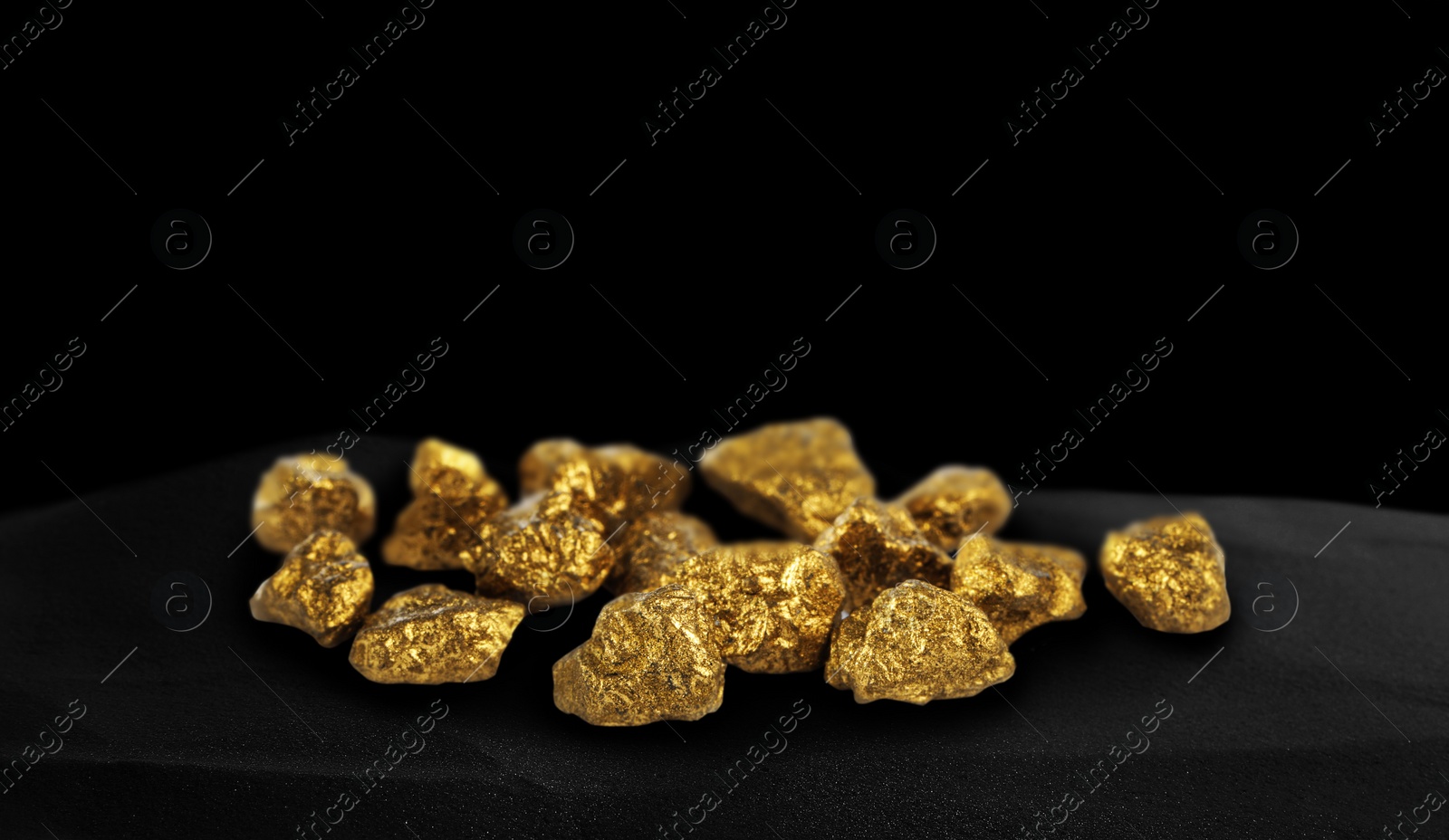 Image of Shiny gold nuggets on black sand, space for text