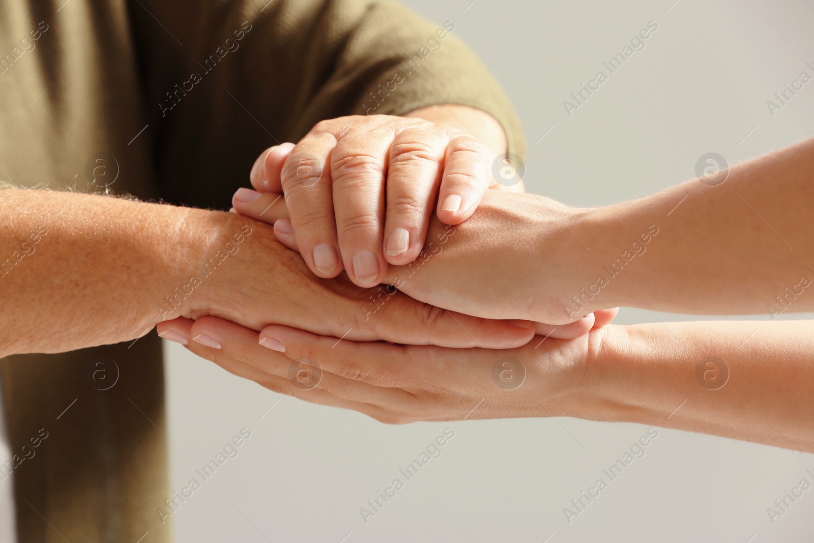 Photo of Helping hands on gray background, closeup. Elderly care concept