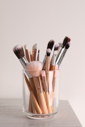 Photo of Set of professional brushes on wooden table against white background