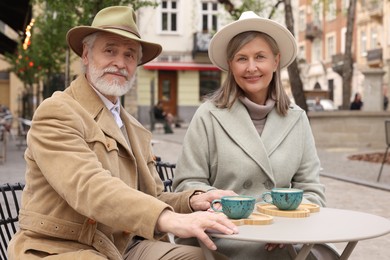 Photo of Portrait of affectionate senior couple with coffee sitting in outdoor cafe
