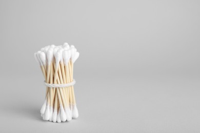 Photo of Bunch of wooden cotton buds on light grey background. Space for text