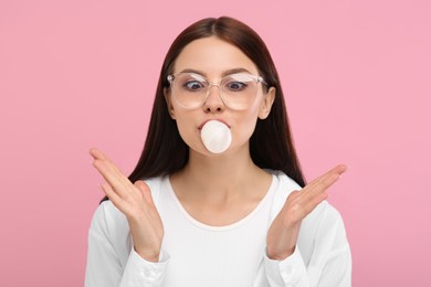 Photo of Beautiful woman blowing bubble gum on pink background