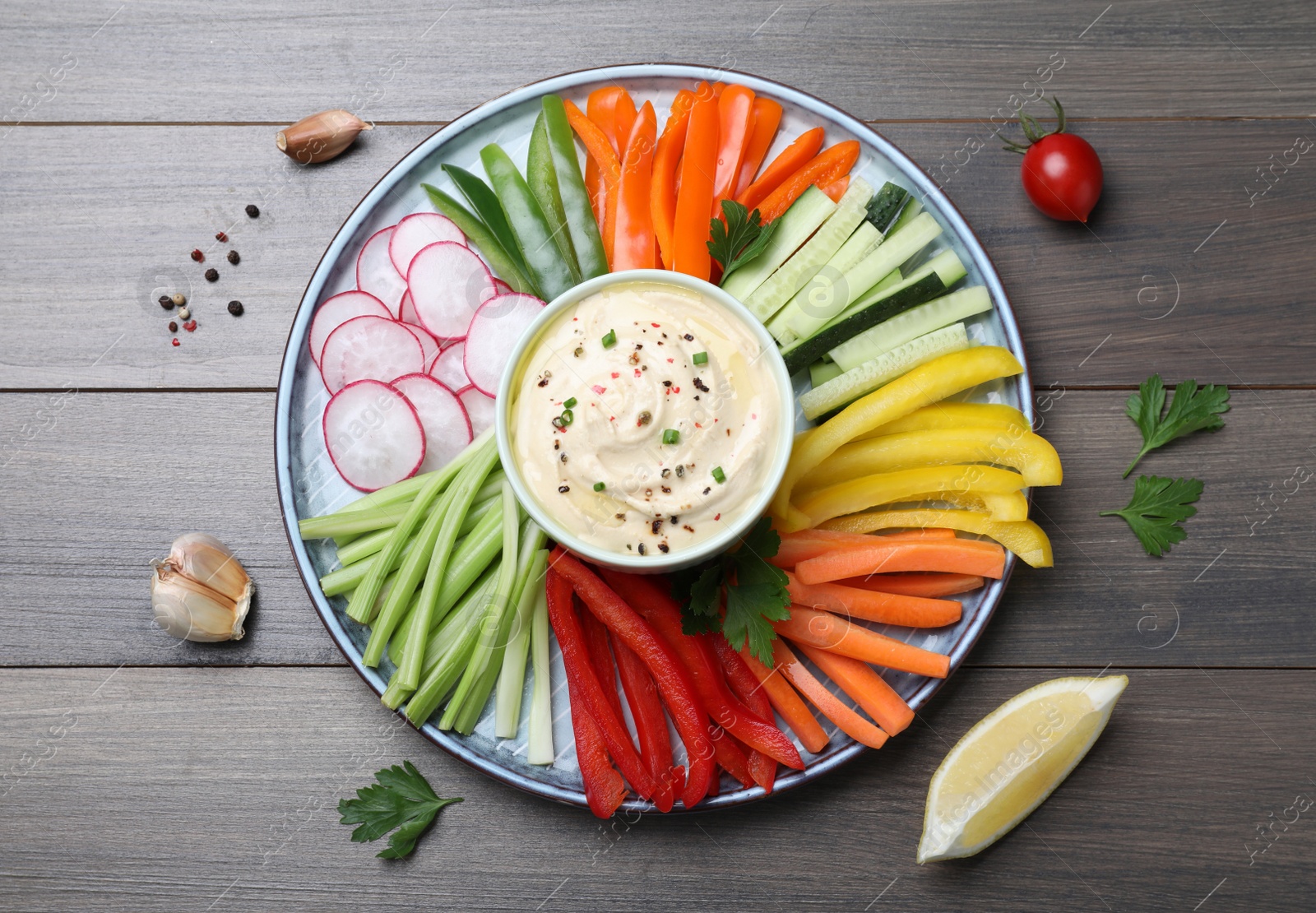 Photo of Fresh raw vegetable sticks and sauce on grey wooden table, flat lay