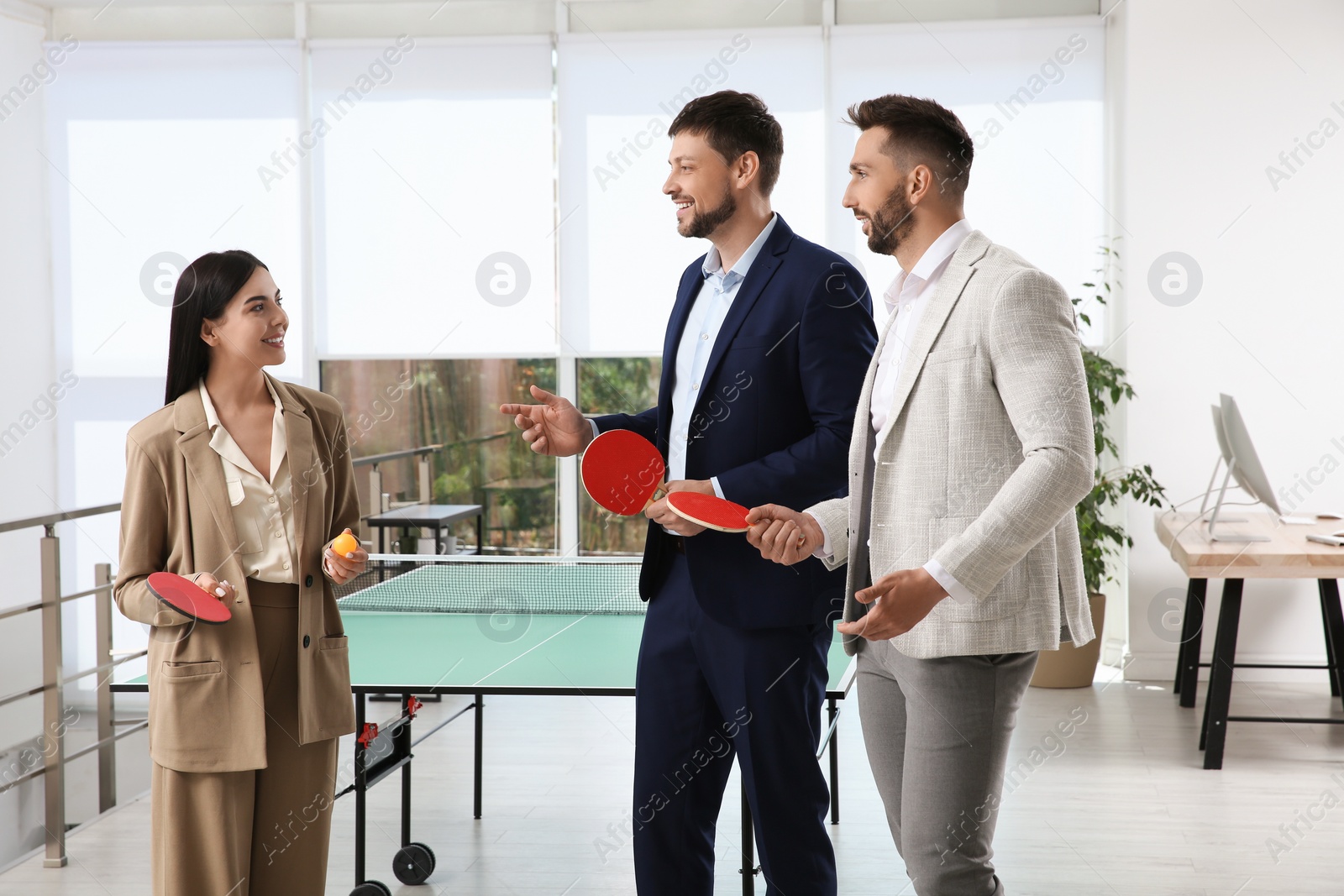 Photo of Business people talking near ping pong table in office