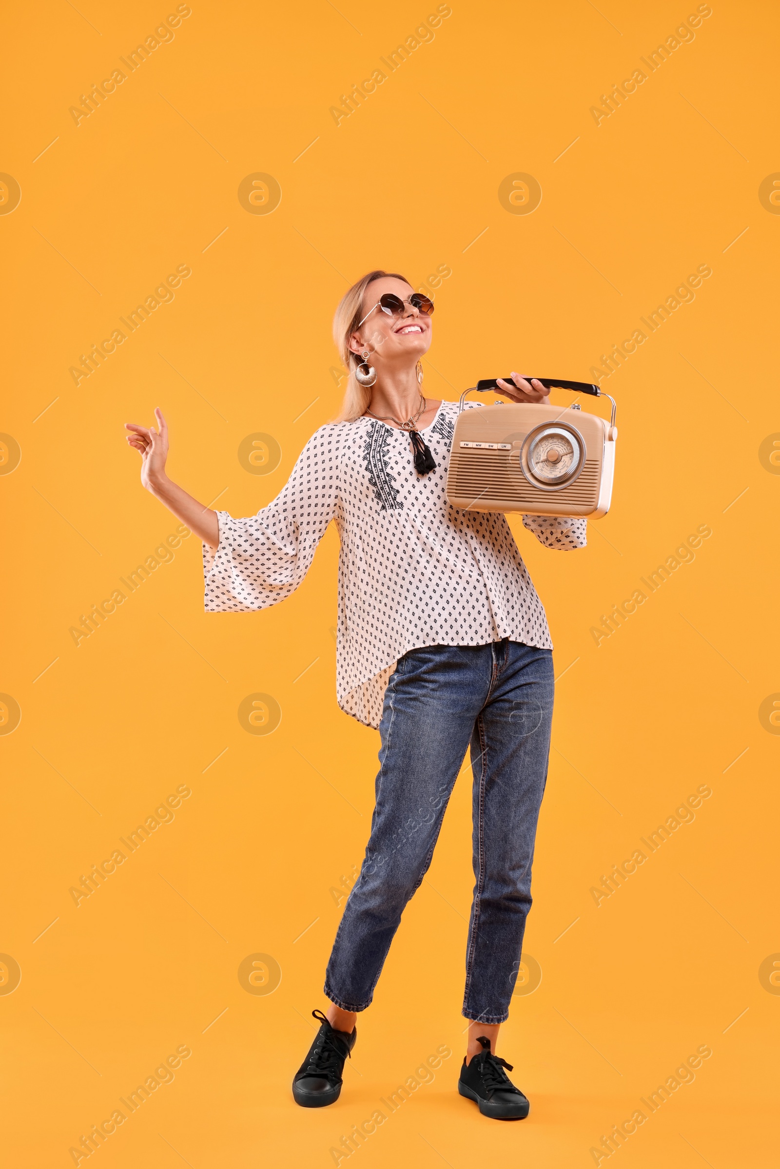 Photo of Portrait of happy hippie woman with retro radio receiver on yellow background