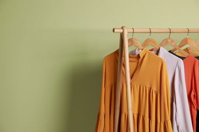 Photo of Collection of trendy women's garments on rack near green wall, space for text. Clothing rental service