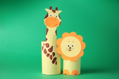Photo of Toy giraffe and lion made from toilet paper hubs on green background. Children's handmade ideas