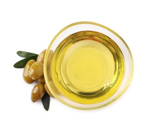Photo of Glass bowl of oil, ripe olives and green leaves on white background, top view