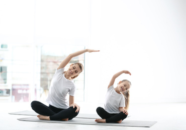 Mother and daughter in matching sportswear doing yoga together at home