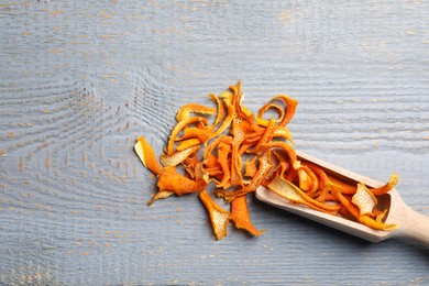 Scoop with dry orange peels on wooden table, flat lay. Space for text