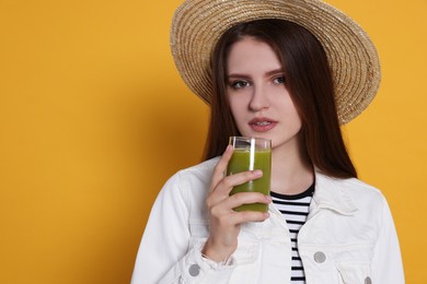 Beautiful young woman with glass of juice on yellow background. Space for text