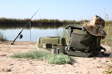 Bag with fishing essentials at riverside on sunny day