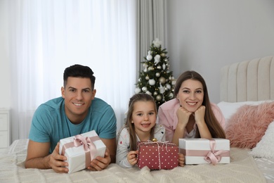 Photo of Portrait of happy family with Christmas gifts on bed at home