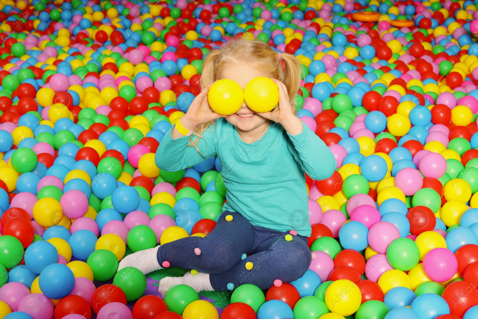 Photo of Cute child playing in ball pit indoors