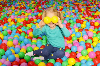 Cute child playing in ball pit indoors