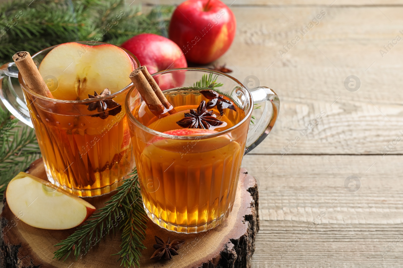 Photo of Hot mulled cider, ingredients and fir branches on wooden table