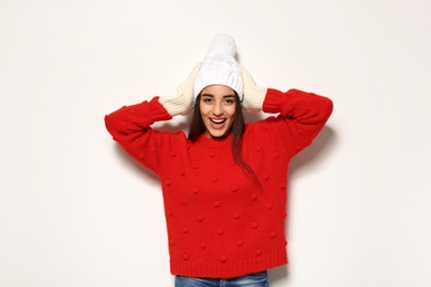 Young woman in warm sweater and hat on white background. Celebrating Christmas