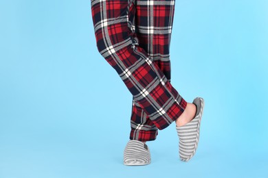 Photo of Man in warm soft slippers on light blue background, closeup