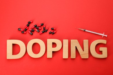 Word Doping and drugs on red background, flat lay
