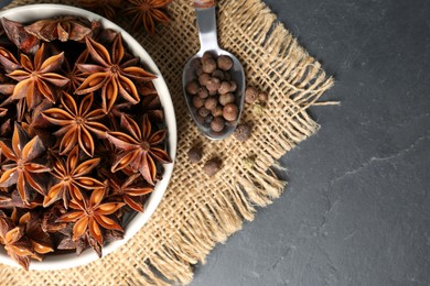 Photo of Bowl with aromatic anise stars and pepper on dark table, flat lay. Space for text