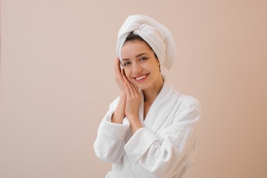 Beautiful young woman with hair wrapped in towel after washing on beige background