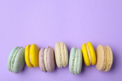 Delicious colorful macarons on violet background, flat lay. Space for text