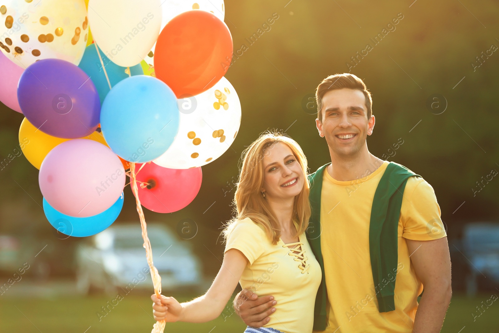 Photo of Young couple with colorful balloons outdoors on sunny day