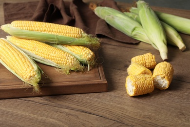 Tasty sweet corn cobs on wooden table