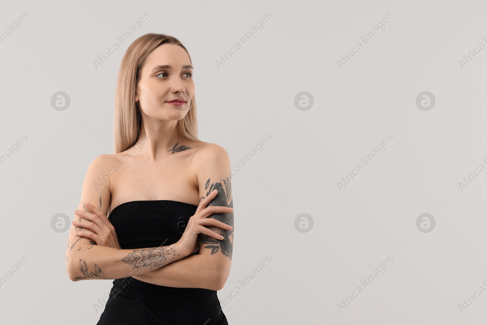 Photo of Beautiful tattooed woman on light background, space for text