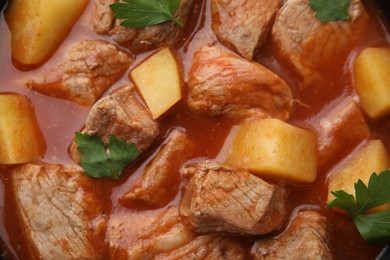 Photo of Delicious goulash with parsley as background, closeup